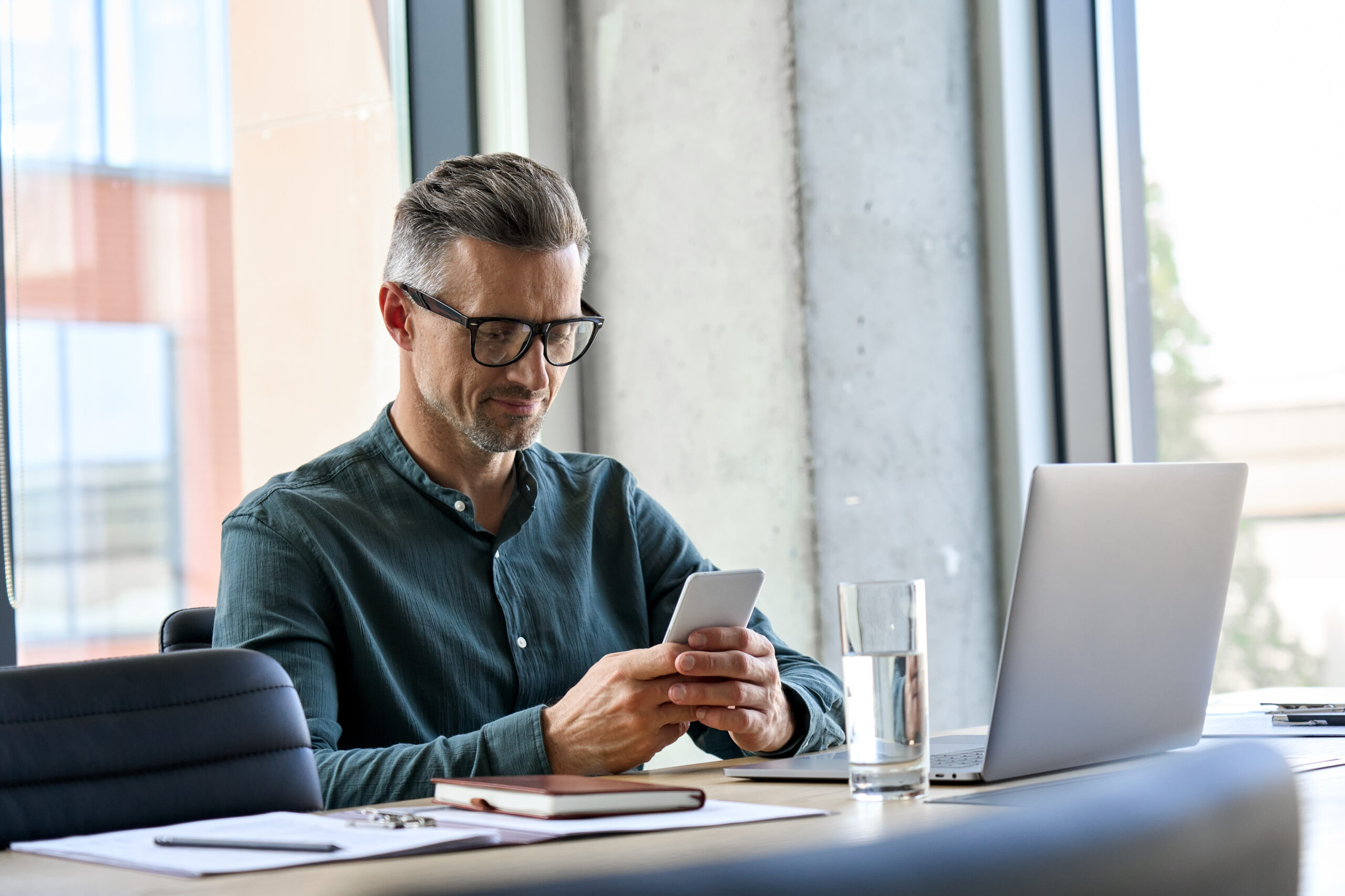Smiling,Mature,Businessman,Holding,Smartphone,Sitting,In,Office.,Middle,Aged Smilende, Eldre, Forretningsmann, Holder, Smarttelefon, Sitter, På, Kontor., Middels, Alder